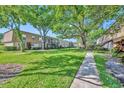 Exterior view showcasing the lush landscaping and mature trees surrounding the condo buildings at 200 Saint Andrews Blvd # 1603, Winter Park, FL 32792
