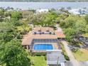 Aerial view of a home featuring a screened-in pool and lush greenery near the water at 639 John Anderson Dr, Ormond Beach, FL 32176