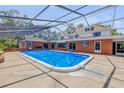 Large screened-in pool with an attached brick home and multiple sliding glass doors at 639 John Anderson Dr, Ormond Beach, FL 32176