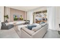 Bright living room with modern decor, neutral tones, large sliding glass doors to the screened-in patio at 7487 Oakmoss Loop, Davenport, FL 33837