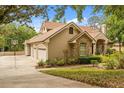 View of home with three-car garage, brick and stucco facade, and lush landscaping at 8800 Torey Pines Ter, Orlando, FL 32819