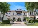 Elegant home showcases a stucco exterior, Spanish-tile roof, arched doorway, and manicured landscaping at 10138 Enchanted Oak Dr, Golden Oak, FL 32836