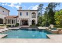 Expansive pool and spa area with travertine deck, and covered patio for relaxing by the water at 10138 Enchanted Oak Dr, Golden Oak, FL 32836