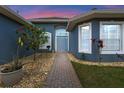 Inviting front entrance with a stone pathway, lush landscaping, and a charming blue-painted facade at 10662 Woodchase Cir, Orlando, FL 32836
