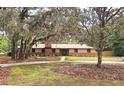 Charming home with mature trees, brick accents, a well-manicured lawn, and a circular driveway at 1212 Foxfire Dr, Apopka, FL 32712