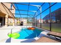 Inviting screened-in pool area features a clear blue pool, patio seating and a built-in grill for outdoor entertaining at 4420 Shiva Loop, Kissimmee, FL 34746