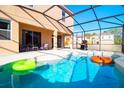 Inviting screened-in pool area features a clear blue pool, patio seating and a built-in grill for outdoor entertaining at 4420 Shiva Loop, Kissimmee, FL 34746