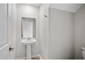 Powder room with pedestal sink, decorative mirror, brushed nickel hardware, and neutral flooring at 4423 Blackbird St, Kissimmee, FL 34746