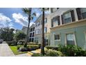 Attractive condo building with tropical landscaping, mature palms, and colorful facade at 11446 Jasper Kay Terrace # 202, Windermere, FL 34786