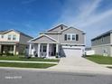 Attractive two-story home boasts a gray exterior, covered front porch, manicured lawn, and a driveway leading to a garage at 1803 Perch Hammock Loop, Groveland, FL 34736