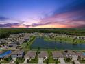 Wide aerial view of a residential neighborhood with homes surrounding a lake and green spaces at 3348 Perennial Ln, Kissimmee, FL 34746