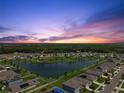 Sunset aerial view of a well-maintained community with a lake and manicured lawns at 3348 Perennial Ln, Kissimmee, FL 34746