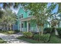 Charming two-story home featuring a welcoming front porch, lush landscaping, and a vibrant turquoise exterior at 8340 Laureate Blvd, Orlando, FL 32827