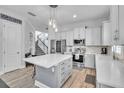 Modern kitchen with stainless steel appliances, a large island with quartz countertops, and stylish pendant lighting at 8340 Laureate Blvd, Orlando, FL 32827