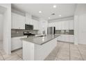 Modern kitchen with stainless steel appliances, gray backsplash, spacious island, and ample white cabinetry at 14154 Shocklach Dr, Winter Garden, FL 34787