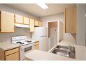 Functional kitchen featuring standard appliances, light wood cabinets, and a double sink at 6506 Swissco Dr # 1317, Orlando, FL 32822