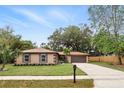 Inviting single-story home featuring a two-car garage, manicured lawn, and mature trees at 100 Des Pinar Ln, Longwood, FL 32750