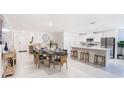 Open-concept dining area showcasing a modern table set, kitchen island, and stainless steel appliances at 114 Tulip Ln, Poinciana, FL 34759
