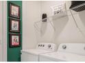 Bright laundry room features side by side washer/dryer, dog themed art and a wire storage shelf at 1218 Alstonia Ln, Mount Dora, FL 32757