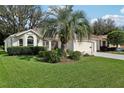 Inviting single-story home with lush green lawn, mature palm tree, and well-maintained landscaping at 1309 Carolina Ct, The Villages, FL 32162