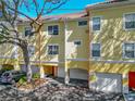 Two-story yellow townhouse with a tile roof and garage, shaded by mature tree at 2329 Shadow View Cir # 2329, Maitland, FL 32751