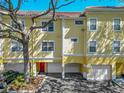 Two-story yellow townhouse with a tile roof and garage, shaded by mature tree at 2329 Shadow View Cir # 2329, Maitland, FL 32751