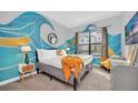 Bright bedroom with a wave mural, comfortable bed, and natural light from the window at 235 Villa Domani Cir, Davenport, FL 33896
