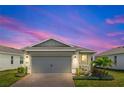 Home featuring a brick paver driveway leading up to a two-car garage and a neatly landscaped garden at dusk at 2457 Cliff Way, St Cloud, FL 34771