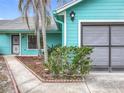 Up-close view of the turquoise siding, gray garage door, and manicured landscaping along the front walkway at 2558 Academy Ave, Deltona, FL 32738