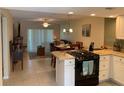 Open kitchen with white cabinets, black appliances, granite countertops, and an adjacent dining area at 325 N Causeway # D104, New Smyrna Beach, FL 32169