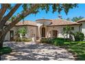 Elegant stucco home with a red tile roof, arched entrance, mature trees, and a circular paver drive at 3412 Lilas Ct, Windermere, FL 34786