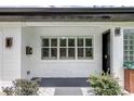 Inviting front porch with a white brick wall, black door, and decorative plants, offering a stylish entryway at 532 Darcey Dr, Winter Park, FL 32792