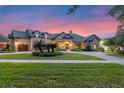 Lovely exterior with meticulous landscaping and a paver driveway illuminated at dusk at 5640 Brookline Dr, Orlando, FL 32819