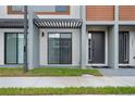 Townhome exterior featuring modern design elements, covered entryway, and tidy front lawn at 8802 Positivity Dr, Kissimmee, FL 34747