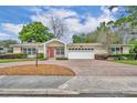 Charming single-story home with a red door, lush landscaping, and a spacious brick driveway at 1329 Maury Rd, Orlando, FL 32804