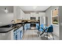 Modern kitchen featuring white and blue cabinets, stainless steel appliances, and an eat-in table at 2256 Betsy Ross Ln, St Cloud, FL 34769