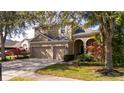 Beautiful tan two-story home with a two car garage, arched entryway, and mature landscaping at 2602 Shirehall Ln, Winter Garden, FL 34787