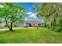 Landscaped front yard featuring a grey garage door, red door, stone facade, and well-maintained lawn at 275 W 3Rd St, Chuluota, FL 32766