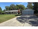 Wide concrete driveway leading to a cozy one-story home with a detached two car garage at 12015 Se 72Nd Court Rd, Belleview, FL 34420
