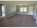 Spacious living room featuring neutral walls, plush carpeting, and natural light through a large window at 1312 Simmons Rd, Kissimmee, FL 34744