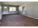 Cozy living room with neutral walls, plush carpeting, a front entry door, and plenty of natural light at 1312 Simmons Rd, Kissimmee, FL 34744