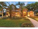 Well-maintained two-story home featuring lush landscaping, a stone walkway, and warm exterior lighting at 1544 Hunters Mill Pl, Oviedo, FL 32765