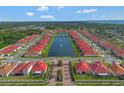 Expansive aerial view of a community featuring vibrant red tile roofs and a central lake at 2335 Symphony Cir, St Cloud, FL 34771