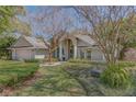 Inviting home featuring an arched entryway, manicured lawn, lush landscaping, and a cozy bench at 320 Remington Dr, Oviedo, FL 32765
