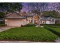 Twilight view of a cozy home featuring a well-kept lawn, inviting entryway, and garage at 320 Remington Dr, Oviedo, FL 32765
