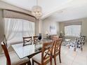 Elegant dining area featuring a glass table, chandelier, and large windows with sheer curtains for natural light at 330 Rosso Dr, Davenport, FL 33837