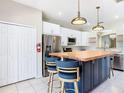 Modern kitchen showcasing a center island with wooden countertop, stainless steel appliances, and white cabinetry at 330 Rosso Dr, Davenport, FL 33837