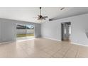 Spacious living room featuring neutral paint, tile flooring, a ceiling fan, and sliding glass doors to the backyard at 408 Magpie Ct, Kissimmee, FL 34759