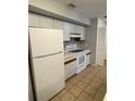 Functional kitchen with white appliances, tiled floor, and ample cabinet space at 4706 Sutton Ter # 111A2, Orlando, FL 32811