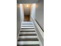 Well-lit stairwell with white risers and grey treads and handrail leading to upper level at 4706 Sutton Ter # 111A2, Orlando, FL 32811
